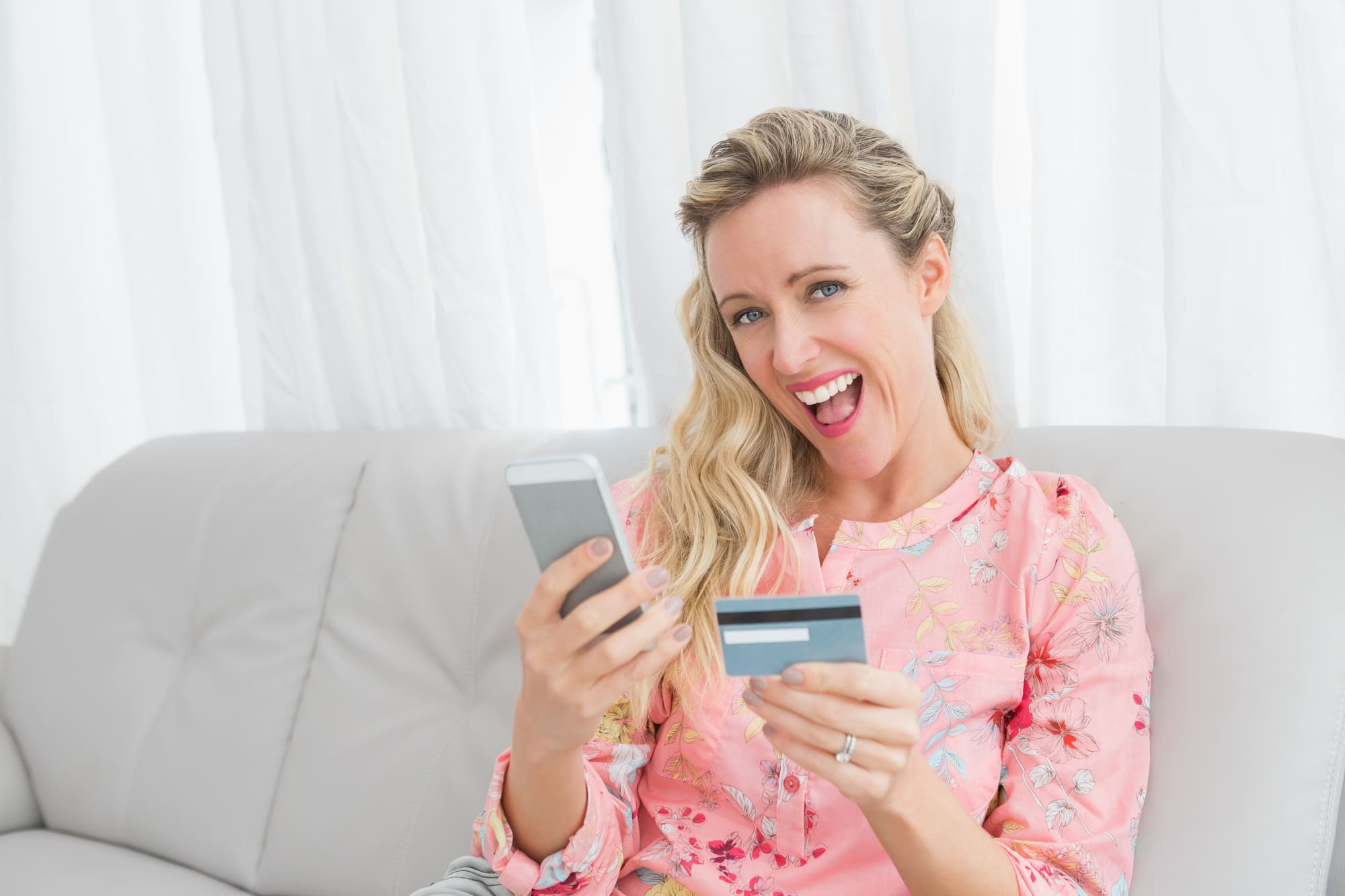 カードを持ちスマホを操作する笑顔の女性