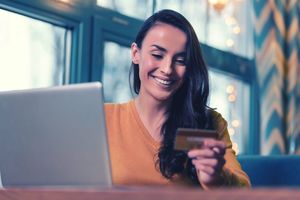 パソコン前でカードを持ち微笑む女性