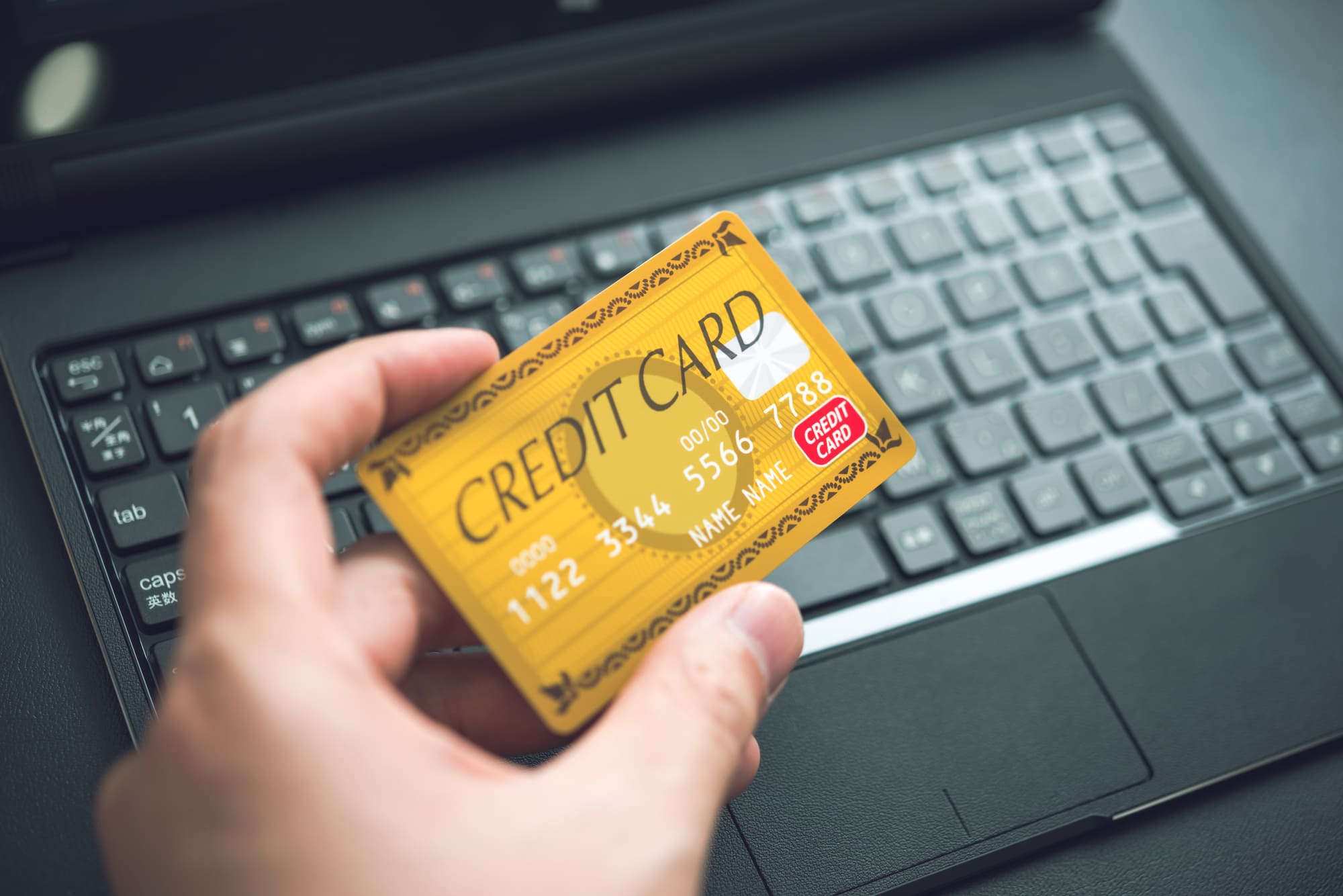 ノートパソコンとクレジットカードと手