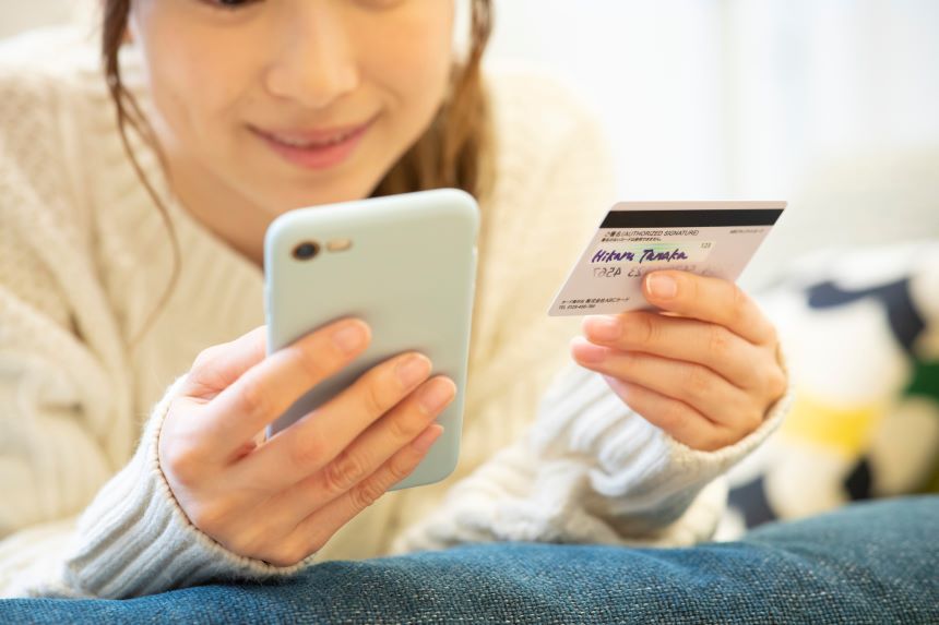 スマホとクレジットカードをみる女性