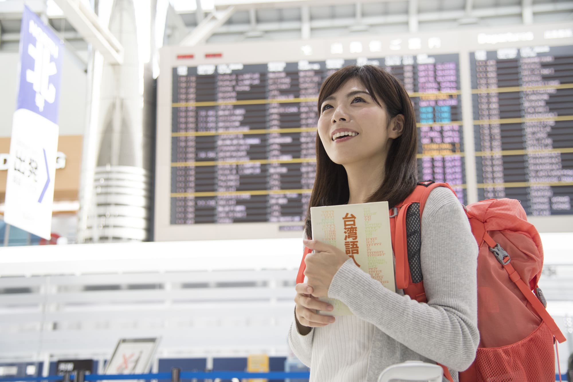 空港でリュックを背負い微笑む女性