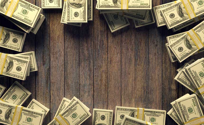 木製のデスクに置かれた100ドル札の束