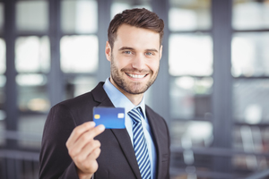 Close-up portrait of happy businessman showing credit card